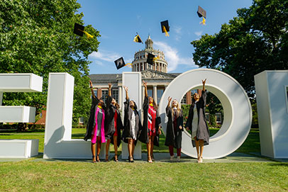 Graduates in front of Meloria sign. Links to Gifts that pay you income. 