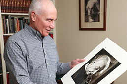 A man looking at a photo of Albert Einstein. Links to Tangible personal property